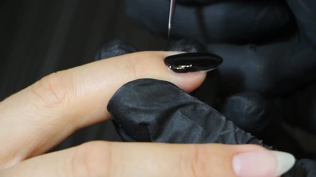 Manicurist's hands are covering gel-polish on the client's nails.