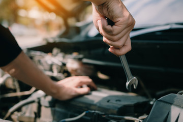 Car mechanic is holding a wrench ready to check the engine and maintenance.