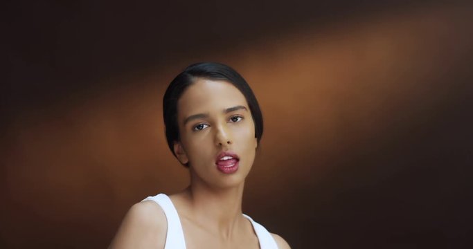 Close up of the the young pretty brunette girl in the white T-shirt mobing like cool girl and dancing in front of the camera. Portrait shot.