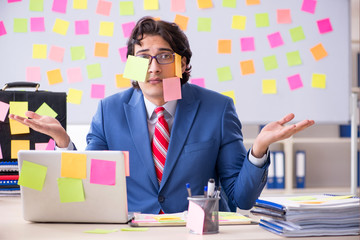 Young male handsome employee in conflicting priorities concept 