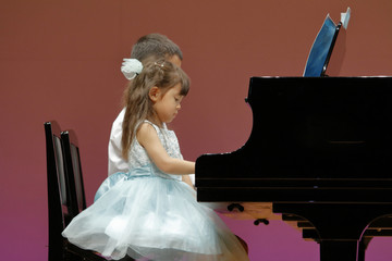 発表会でピアノを弾く兄妹(9歳と4歳)