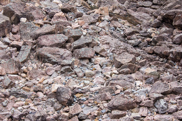 Natural texture of a huge number of stones of large and small size. Danger of rockfalls. Large boulders in the quarry, river gorge, canyon. Rocks broken into pieces of various sizes.
