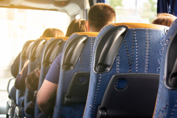 A row of comfortable bus seats and the backs of passengers in them. Travel and tourist trip to...