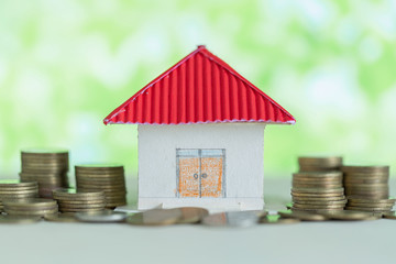 Model of house with coins on wooden table, saving money for buy home concept