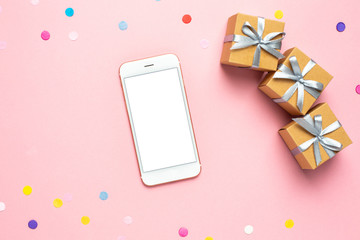 Mobile phone, present boxes and color confetti on pink table. Composition for birthday, mother day or wedding