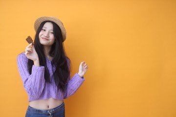 Image of beautiful  woman isolated over yellow wall background holding cake.