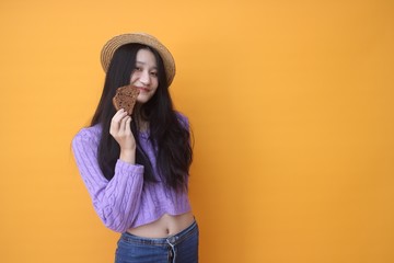 Image of beautiful  woman isolated over yellow wall background holding cake.