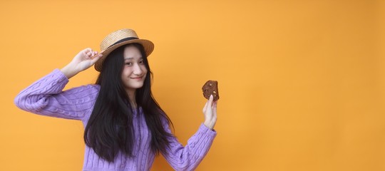 Image of beautiful  woman isolated over yellow wall background holding cake.