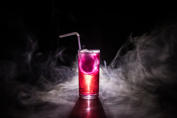 Cocktail glass splashing on dark toned smoky background or colorful cocktail in glass. Party club...