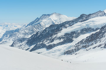 Fototapeta na wymiar Swiss Alps mountain range landscape full of snow in winter, with group of traveler trekking to summit