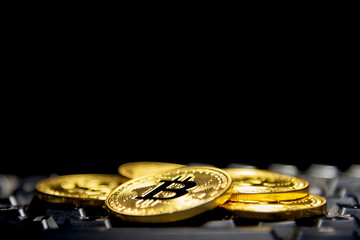 Golden bitcoin on dark keyboard. Spotlight and focus at coin. Dark theme picture. Conceptual image for cryptocurrency.