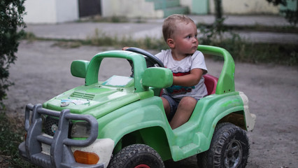 Naklejka premium Little preschool boy driving big toy car and having fun, outdoors.