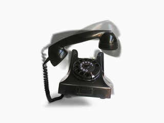 An old fashioned rotary telephone bouncing up and down against a white background