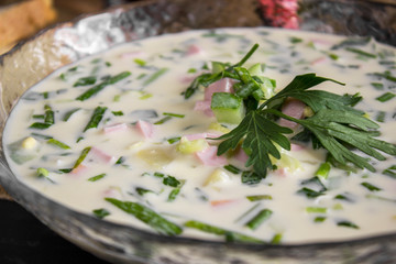Cold Soup Okroshka. With sausage, vegetables and kvass serving size in bowl and raw ingredients on wooden table