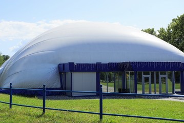 gray tent with a blue glass facade on green grass in nature