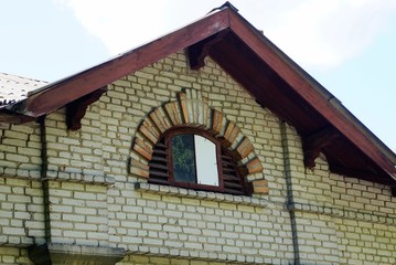 part of an old brown brick attic with a small window against the sky