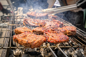 Cooking steak on the grill in the smoke on burning coals