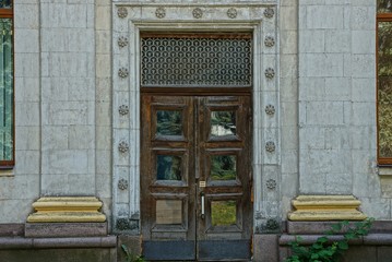  brown old door of wood and glass on a gray concrete wall with columns