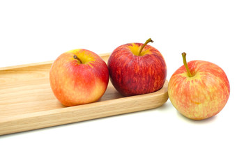 red apple on a wood plate isolated on white	