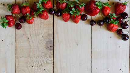 strawberries and cherries on a wooden background