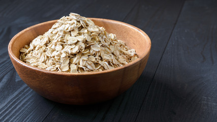 oatmeal in a wooden bowl on a black wooden table