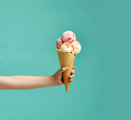 Baby kid hand holding big ice-cream in waffles cone on blue - obrazy, fototapety, plakaty