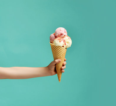 Baby kid hand holding big ice-cream in waffles cone on blue