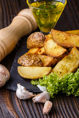 Potato wedges baked in their skins with lettuce on wooden background.