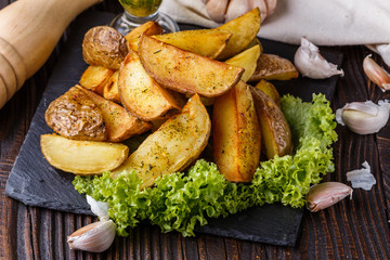 Potato wedges baked in their skins with lettuce on wooden background.