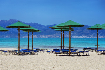 Liegen und Sonnenschirme am Strand mit türkisblauem Wasser
