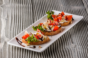 Bruschetta with tomatoes, lettuce, camambert, balsamic vinegar