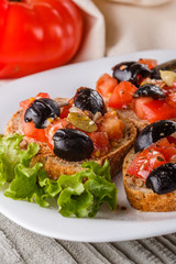Italian bruschetta with tomato, black olives, lettuce and mustard