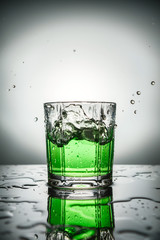 The splashes from the falling ice in green cocktail