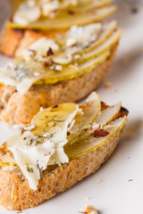 Appetizer bruschetta with pear, honey, walnut and blue cheese on white plate