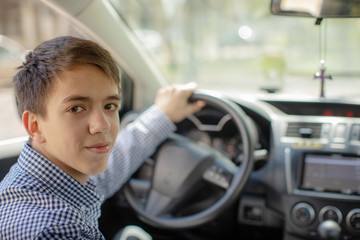 Young boy driving a car. Teen behind the wheel of a car. teenager stole a car