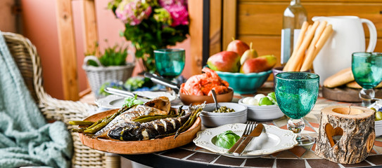 Shrimp in a pan. Dining table with different foods, snacks and flowers. Summer lunch in the open air. Seafood and asparagus.