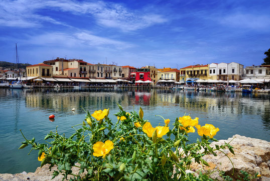 Blick auf die Innenstadt Rethymnon mit gelben Blumen im Vordergrund