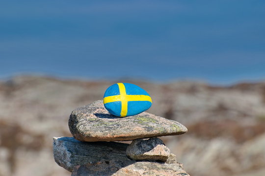 Stone with the image of the Sweden flag on the backround of blue sky. Concept of National Day of Sweden. Celebrate 6 June .