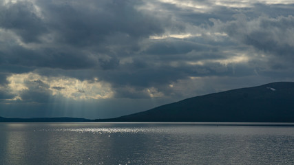 Sunlight through the clouds over the rocky northern lake