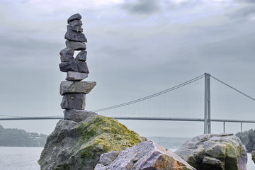 Pyramid of stones on the background of the fjord and the bridge in Norway