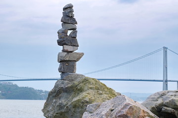 Obraz premium Pyramid of stones on the background of the fjord and the bridge in Norway