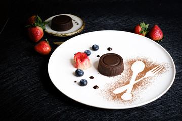 Fototapeta premium Molten chocolate lava cake with berries on white plate.