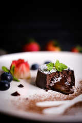Molten chocolate lava cake with berries on white plate.