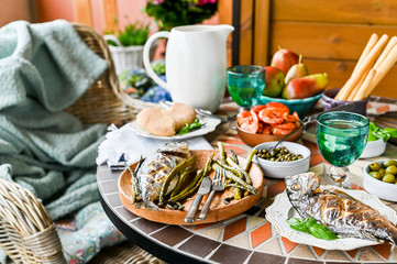 Dining table with different foods, snacks and flowers. Summer lunch in the open air. Seafood and vegetables.  
