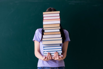 Young female teacher student in front of green board 