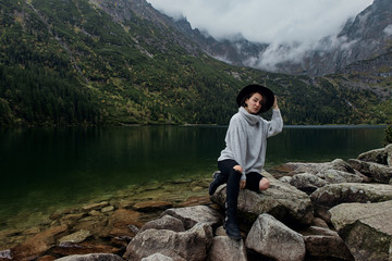 Girl sitting on rocks near lake. Tatra mountains landscape in Poland, Zakopane. Mountain landscape in Eastern Europe.