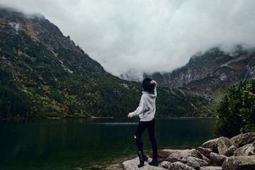 Girl staying on rocks near lake. Tatra mountains landscape in Poland, Zakopane. Mountain landscape in Eastern Europe.