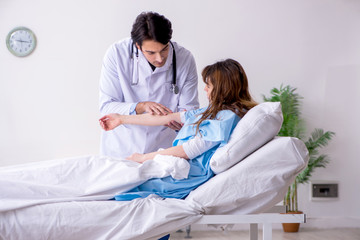 Fototapeta premium Male doctor visiting female patient in ward 