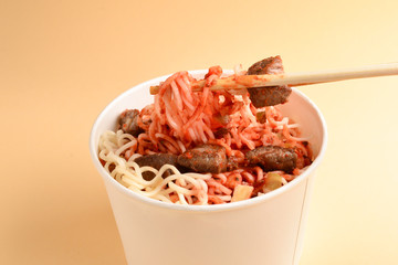 Paper cup with instant ramen noodles with beef and vegetables.
