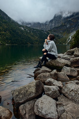 Girl sitting on rocks near lake. Tatra mountains landscape in Poland, Zakopane. Mountain landscape in Eastern Europe.